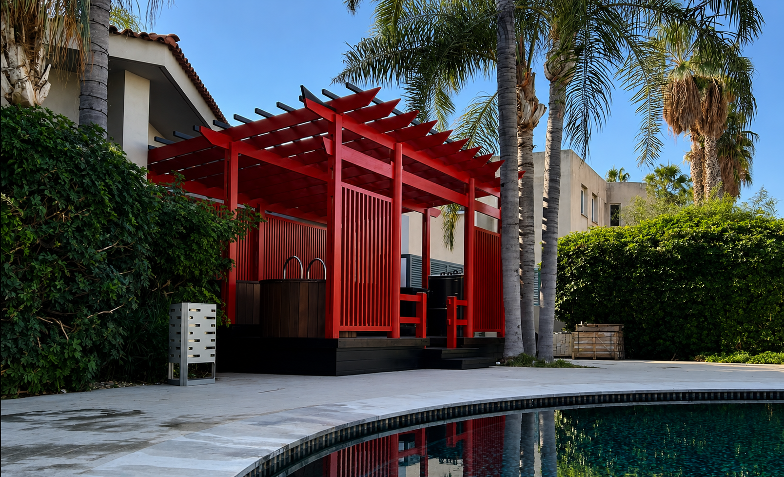 A modern outdoor poolside cabana with a bold red wooden pergola structure and slatted walls, set in a luxurious backyard with palm trees, a swimming pool, and a beige stucco house.